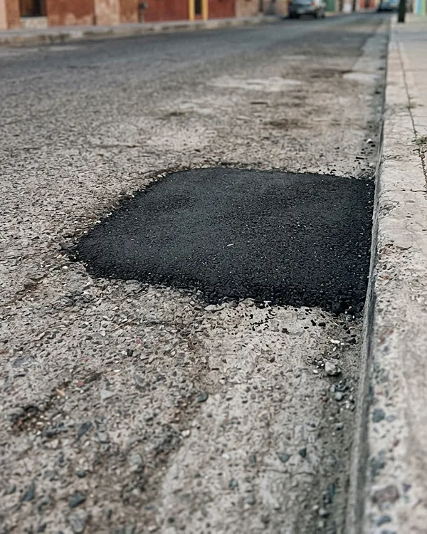Bache reparado con asfalto en frío, liso y al nivel de la calle